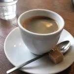 Tasse de café américain, cuillère et sucre sur table en bois rustique
